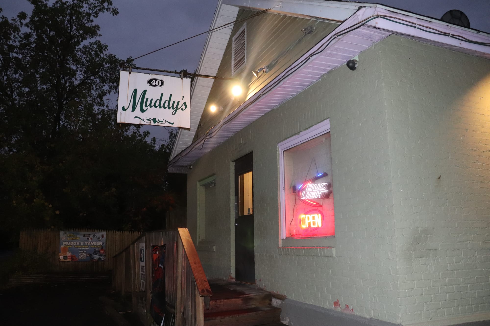 Exterior of Muddy’s Tavern with signage lit up at night.