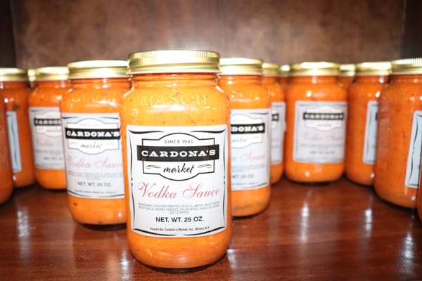 Close-up photo of Cardona's Market jarred vodka sauce displayed on a shelf, showcasing its rich orange-cream color and locally made Italian branding
